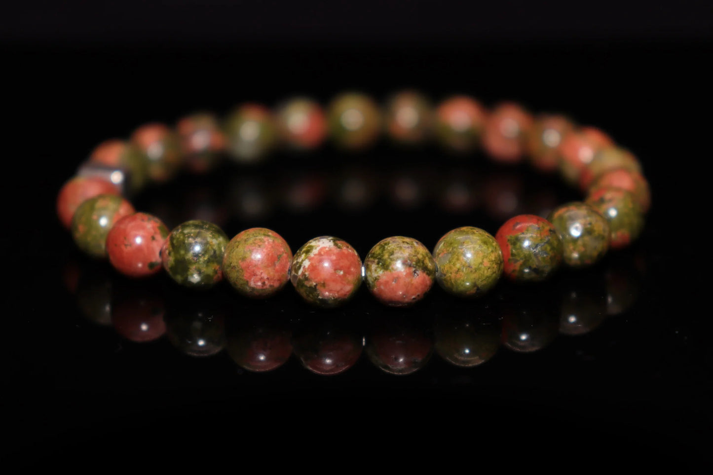 Close-up detail of dragon blood jasper bracelet showing dramatic red speckles on green matrix, Christ blood Renaissance amulet gemstone jewelry
